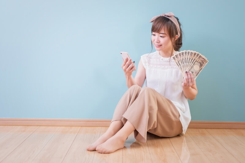 お金とスマホを持つ女性